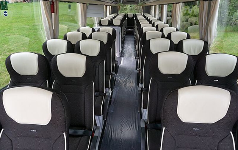 Interior de un autocar grande con asientos reclinables y pasillo central